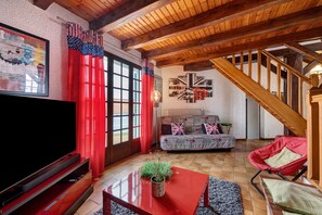 Een woonkamer met een televisie, rode gordijnen, een bank en een trap.