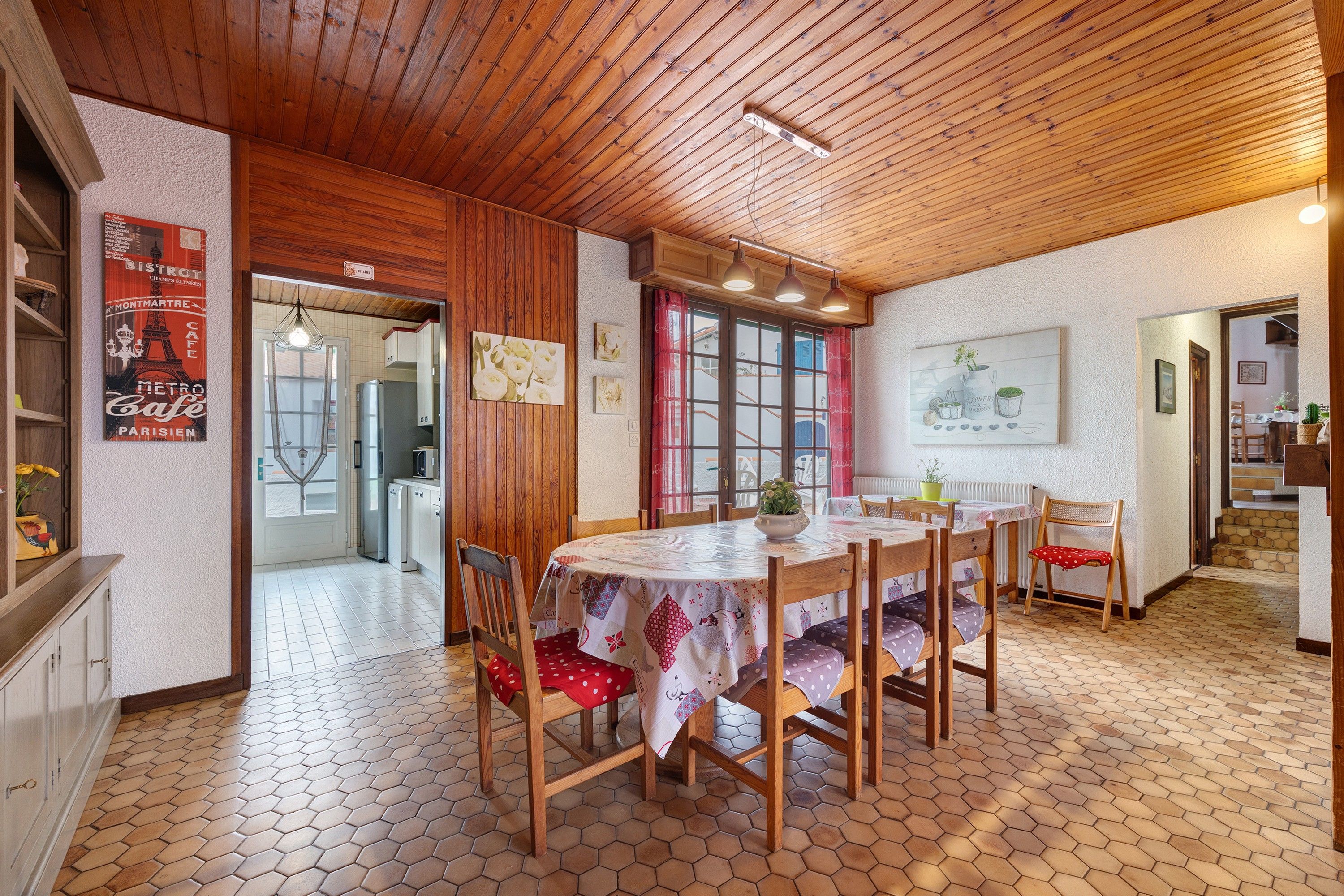 Un espace repas doté d’un plafond en bois, de carreaux de sol hexagonaux et d’une table dressée pour quatre personnes.