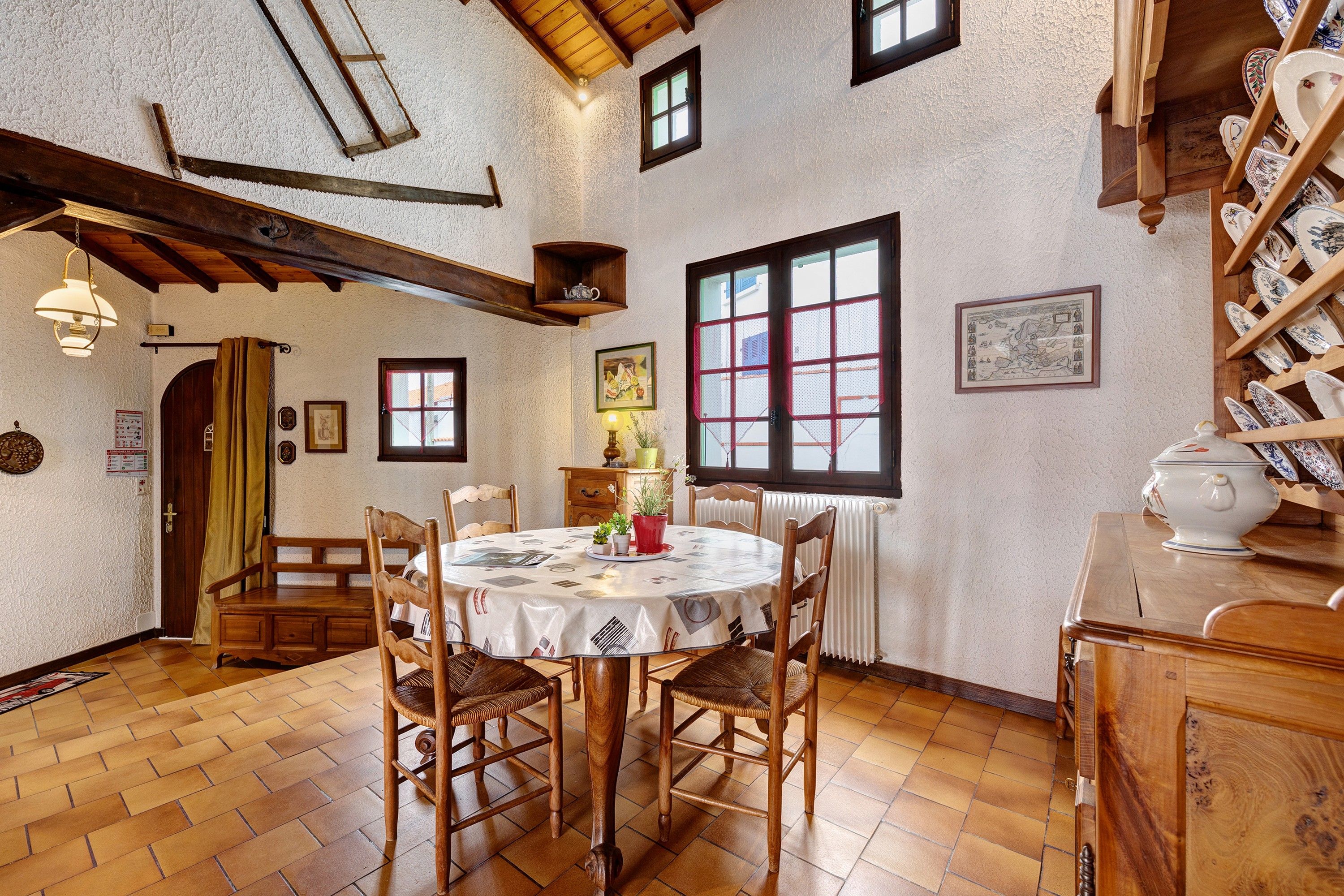 Ein traditioneller Speisesaal mit Holztisch, Stühlen und Fliesenboden.