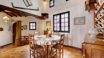 Ein traditioneller Speisesaal mit Holztisch, Stühlen und Fliesenboden.