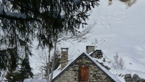 A stone cabin with a wooden door, surrounded by snow-covered ground and trees. - Apartment 'Le Bois De Marie' with Mountain View, Private Terrace and Wi-Fi (Barèges)