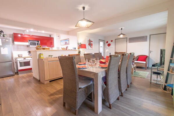 Una cocina moderna con armarios rojos, una zona de comedor con sillas de mimbre y una isla central.