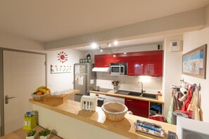 Una cocina moderna con armarios rojos, un microondas y un fregadero.