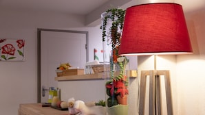 A room with a wooden desk, a lamp with a red shade, a clear vase with plants, and a teddy bear. - Apartment 'Le Bois De Marie' with Mountain View, Private Terrace and Wi-Fi (Barèges)