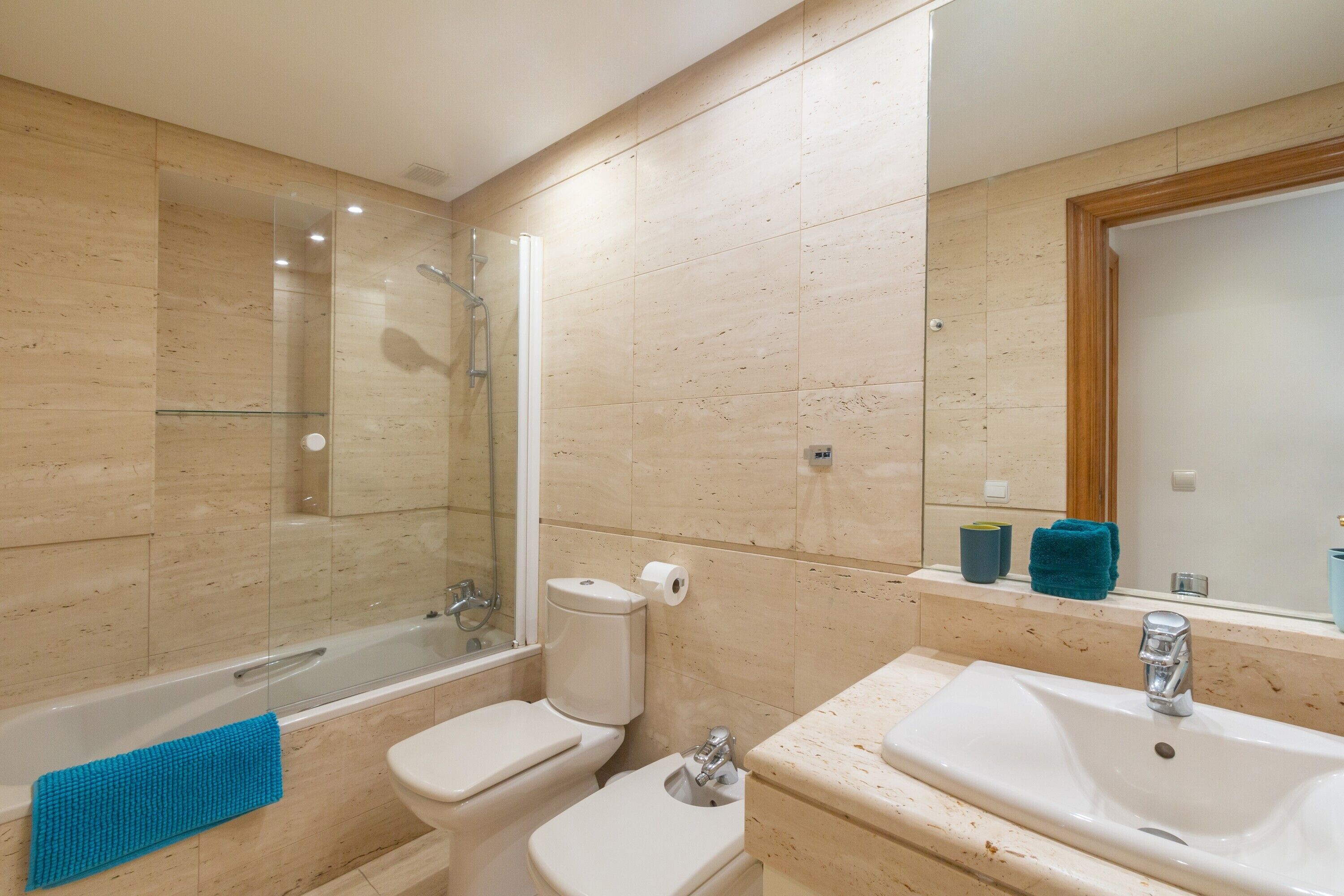 Une salle de bain avec une douche à parois de verre, des toilettes, un lavabo et un miroir.