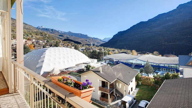 Un edificio residencial con balcón, una estructura en forma de cúpula blanca y vistas a un valle con montañas.