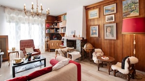 Una sala de estar acogedora con chimenea, estanterías, un sillón rojo y una mesa de centro.