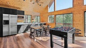 Een ruime keuken met moderne apparatuur, een eethoek met een tafel en stoelen, en een tafelvoetbaltafel.