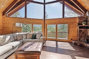 Un intérieur en bois avec un canapé, un pouf et une cheminée.
