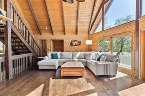 Un salón espacioso con techo de madera, un sofá grande, una mesa de centro y una escalera.