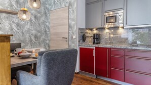 Una cocina moderna con microondas integrado, cafetera y un armario rojo.