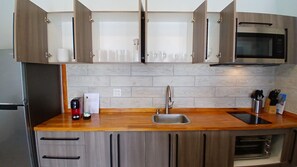 Una cocina moderna con armarios de madera, un lavamanos de acero inoxidable y un microondas.
