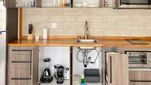 A modern kitchen with wooden cabinets, a stainless steel sink, and a built-in microwave. - Bushiri's Long Life Building-2BD/1BA APT-Sleeps 4 (Oranjestad)