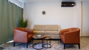A living room with a sofa, two armchairs, a coffee table, and a small potted plant.
