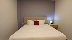 Una habitación de hotel con una cama, una mesita de noche y una lámpara.