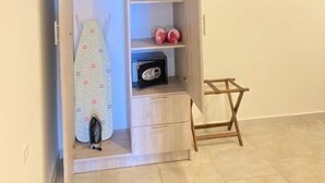 A room with a wooden wardrobe, a small ironing board, and a surfboard. - Bushiri's Long Life Building-2BD/1BA APT-Sleeps 4 (Oranjestad)