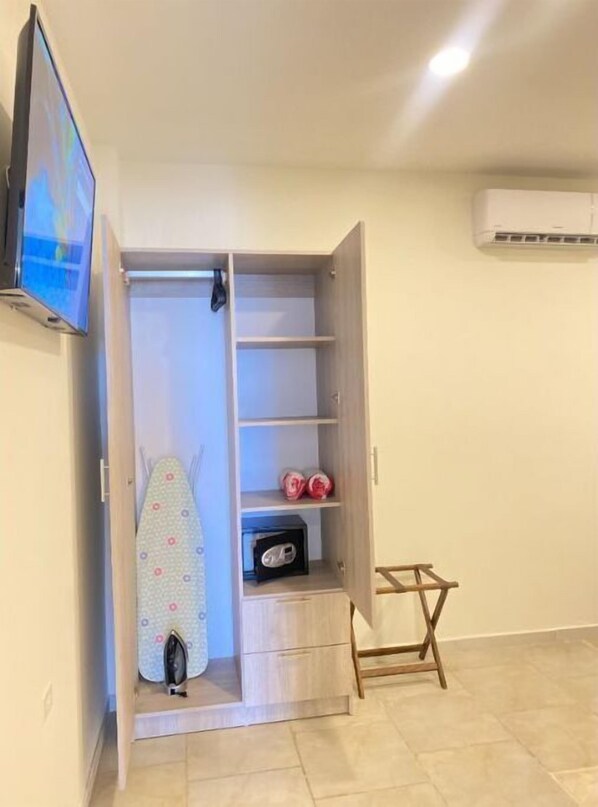 Una habitación con un armario de madera, una plancha pequeña y una tabla de surf.