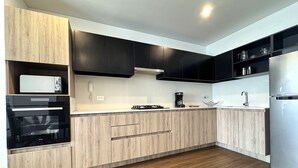 Een moderne keuken met houten kastjes, een inbouwoven, een koffiezetapparaat en een roestvrijstalen koelkast.