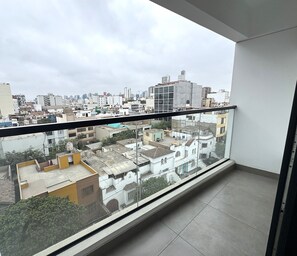 Un balcón con vista a un paisaje urbano, que incluye edificios de diferentes alturas y estilos arquitectónicos.