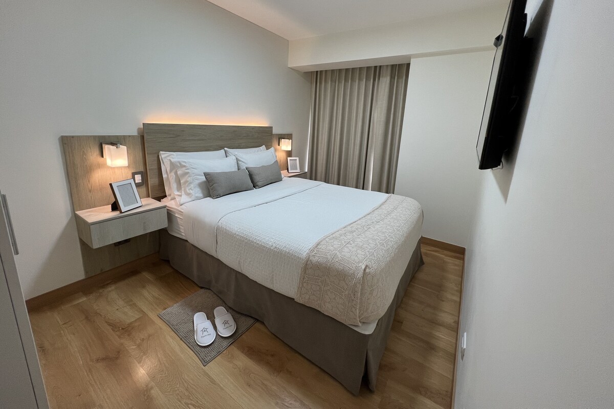 Ein modernes Hotelzimmer mit einem großen Bett, Nachttischen, einem Flachbildfernseher und Holzboden.