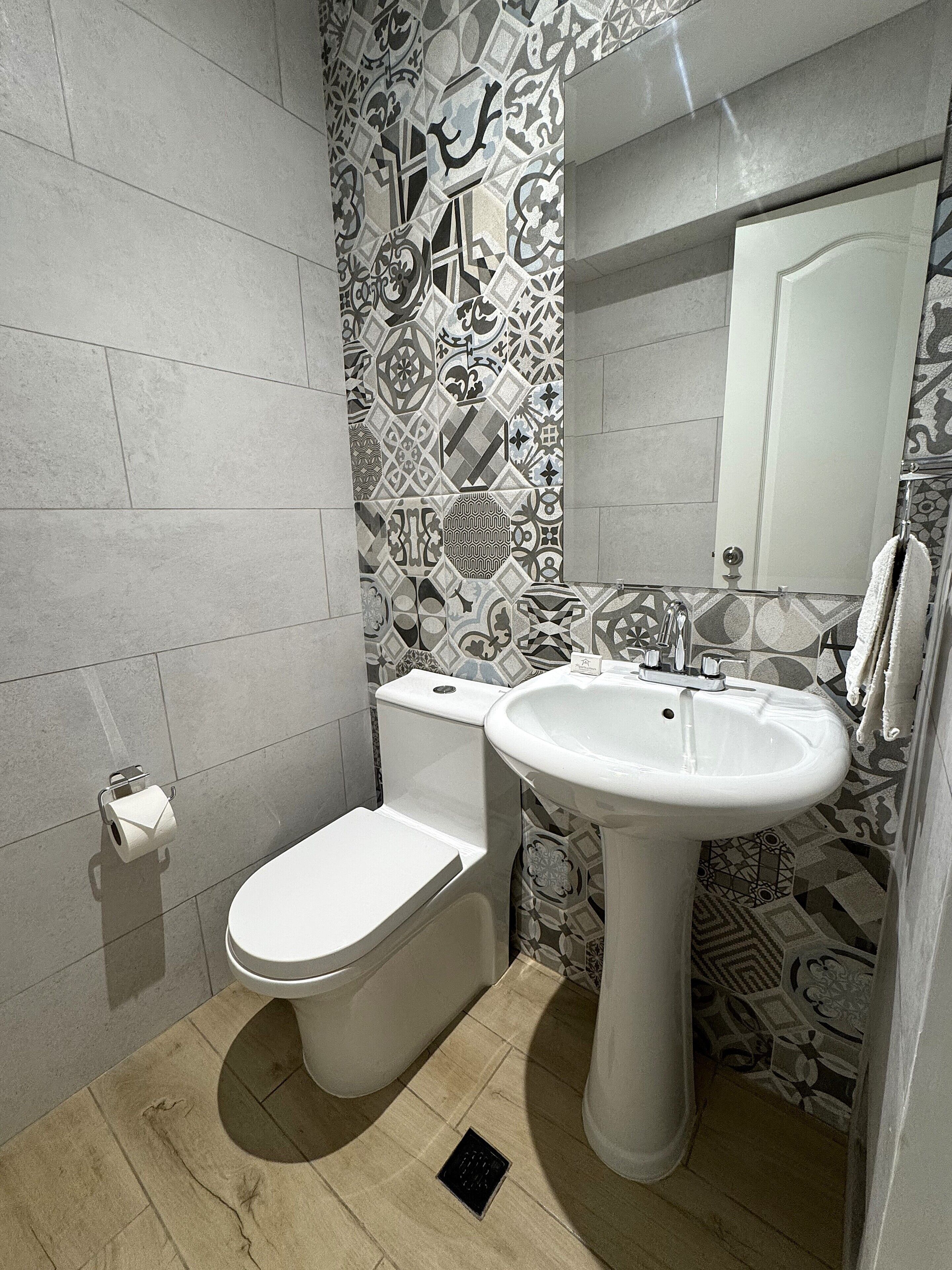 Un baño moderno con inodoro, lavamanos y azulejos estampados.