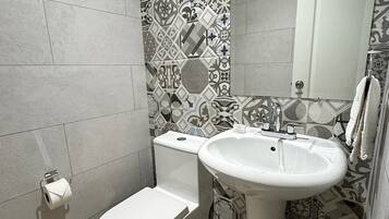 Un baño moderno con inodoro, lavamanos y azulejos estampados.