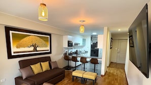 Een moderne woonkamer met een bruine bank, een eettafel gedekt met borden en glazen, en een keuken op de achtergrond.