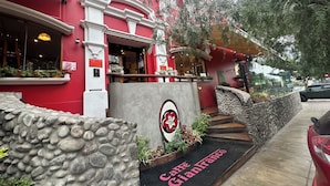 Een rood gebouw met een stenen gevel, een bord met de tekst 'Caffè Gianfranco' en een auto die er geparkeerd staat.