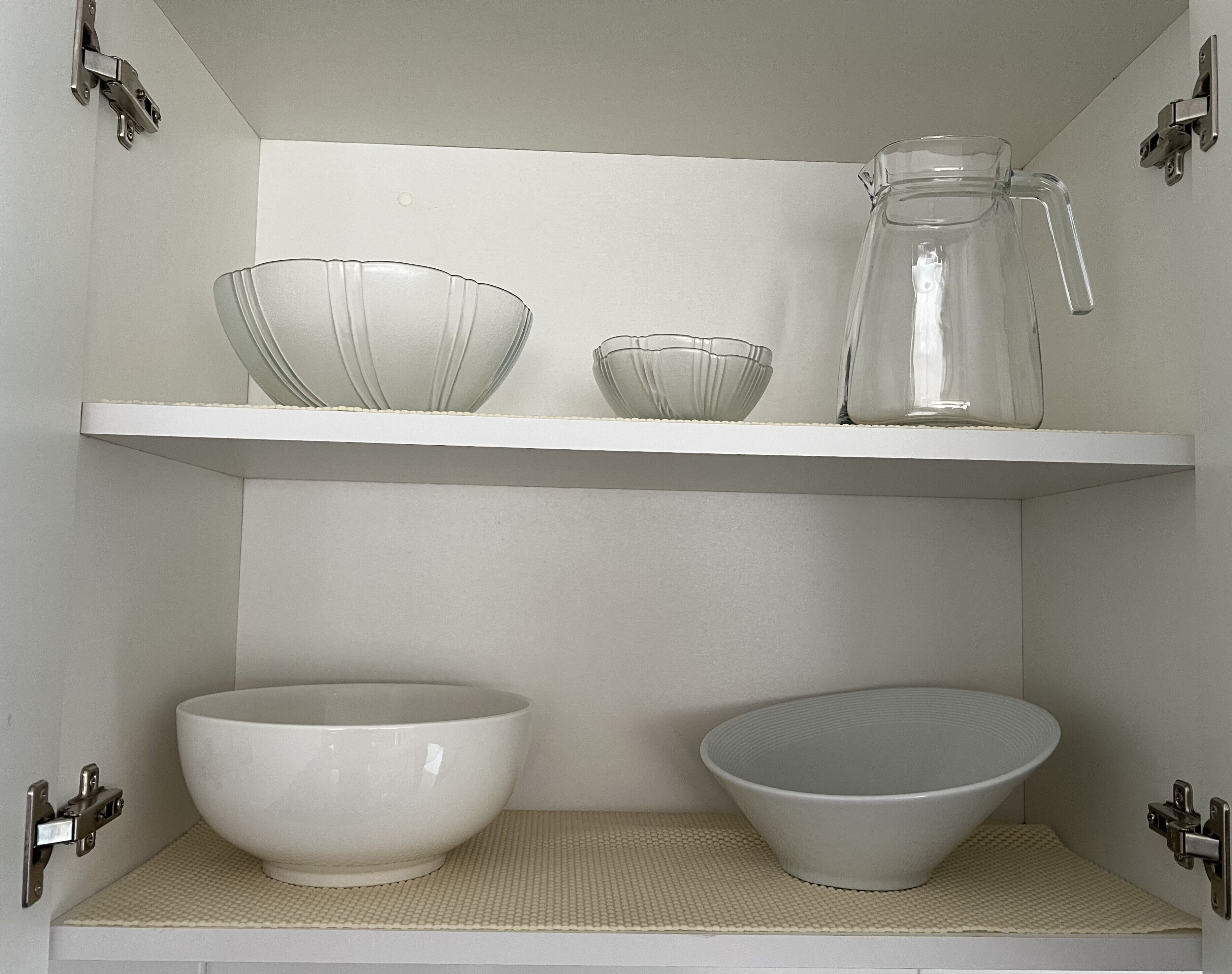 A kitchen shelf with two bowls, a pitcher, and a small bowl.