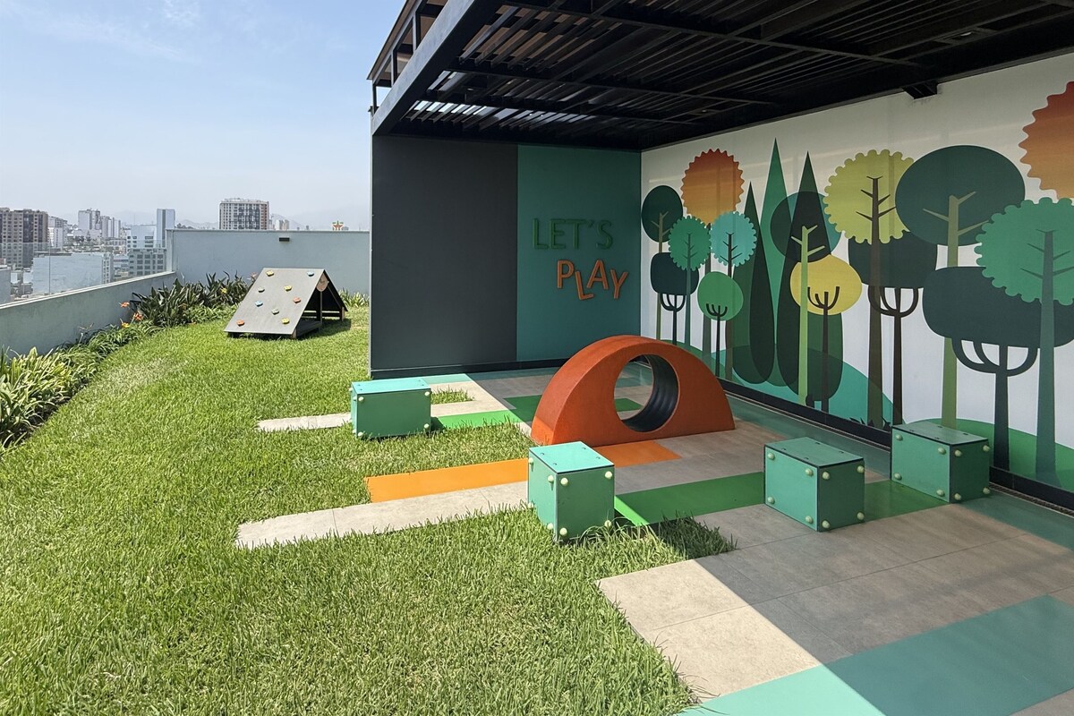 Un espace de jeux sur le toit, comprenant un mur d’escalade, un toboggan et une fresque représentant des arbres ainsi que le texte « JOUONS ENSEMBLE ».