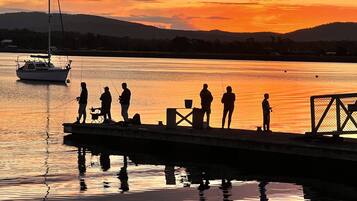 A pier with people fishing at sunset.
