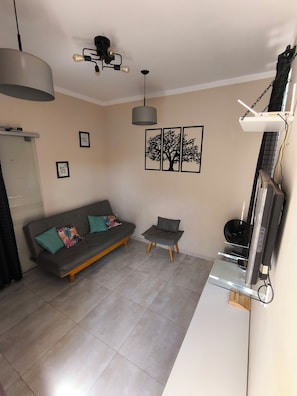 Un salon comprenant un canapé, une petite table, un luminaire au plafond et des œuvres d’art murales.
