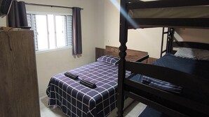 A room with a bunk bed, a desk, a chair, a wardrobe, and a ceiling fan.