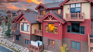 A multi-story building with a balcony, a hot tub, and a view of the surrounding landscape.