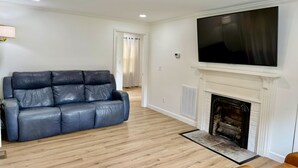 A living room with a blue leather sofa, a fireplace, and a TV mounted above it. - Farmhouse in Livingston  (Livingston)