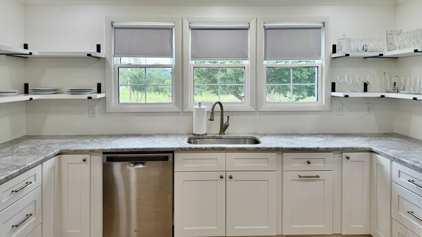 A kitchen with white cabinets, a stainless steel dishwasher, and a window with blinds. - Farmhouse in Livingston  (Livingston)