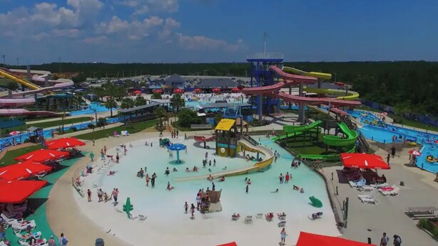 A water park with multiple slides and pools, surrounded by umbrellas and beach chairs.
