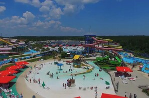 A water park with multiple slides and pools, surrounded by umbrellas and beach chairs. - Relaxed Resort-Style Coastal Villa/Pools/Hot tubs/Gym/2 Min to Beach. Gated! (Gulfport)