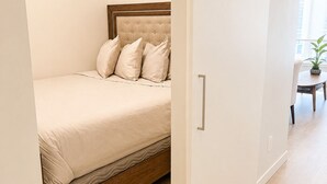 A bedroom with a bed, a wooden headboard, a bedside table, and a potted plant. - One Bedroom Suite in Downtown Sidney (Sidney)