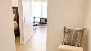 A hallway with a bench, a bed, and a dining area. - One Bedroom Suite in Downtown Sidney (Sidney)