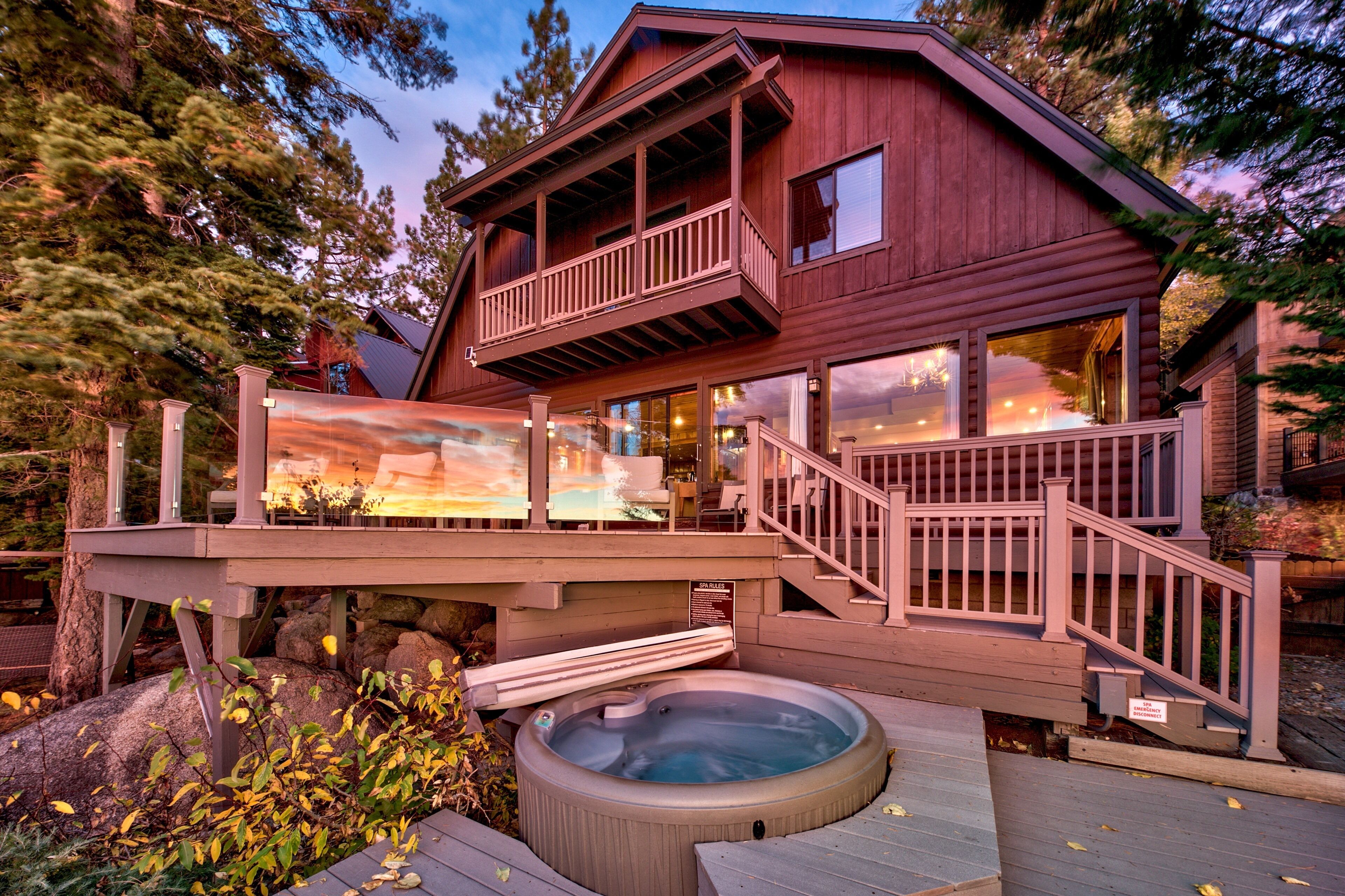 A wooden cabin with a hot tub, deck, and a scenic painting.