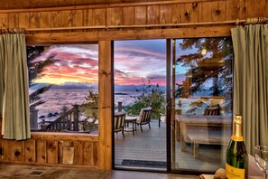 A wooden cabin with a deck, a bottle of champagne, and a glass on the table. - LX6 Lakefront Luxury Estate Cave Rock (Glenbrook)