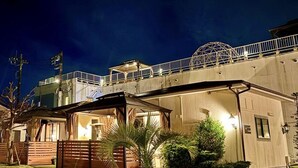 A hotel with a covered outdoor area, a bridge, and a well-lit entrance. - Ducale Garden Hotel 99 (Kujukuri)