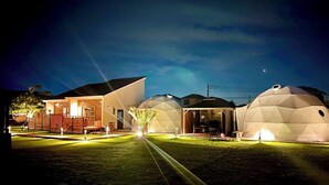 A modern house with a large dome-shaped structure and a well-lit front yard. - Ducale Garden Hotel 99 (Kujukuri)