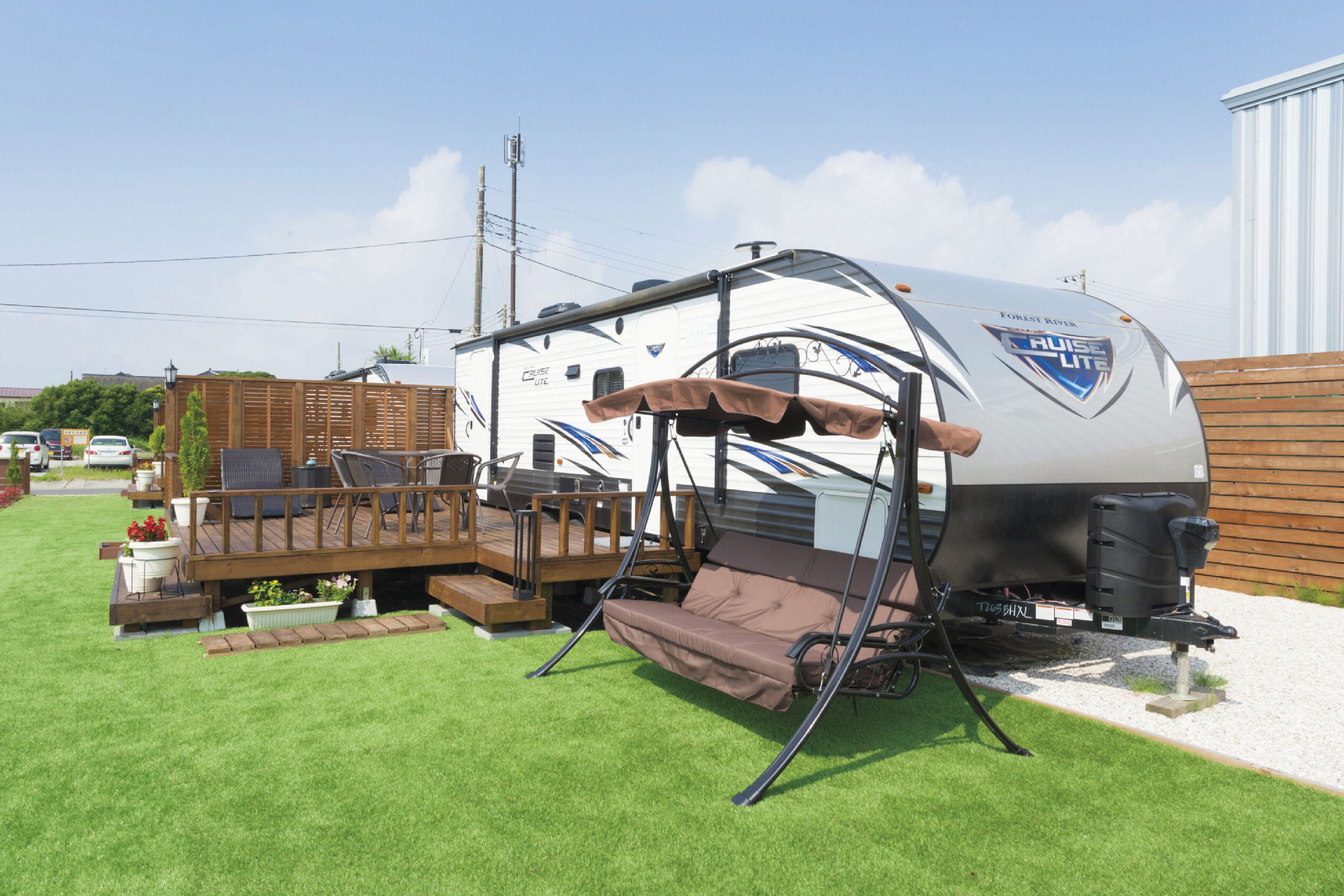 A recreational vehicle with a covered deck, a seating area, and a small outdoor kitchen.