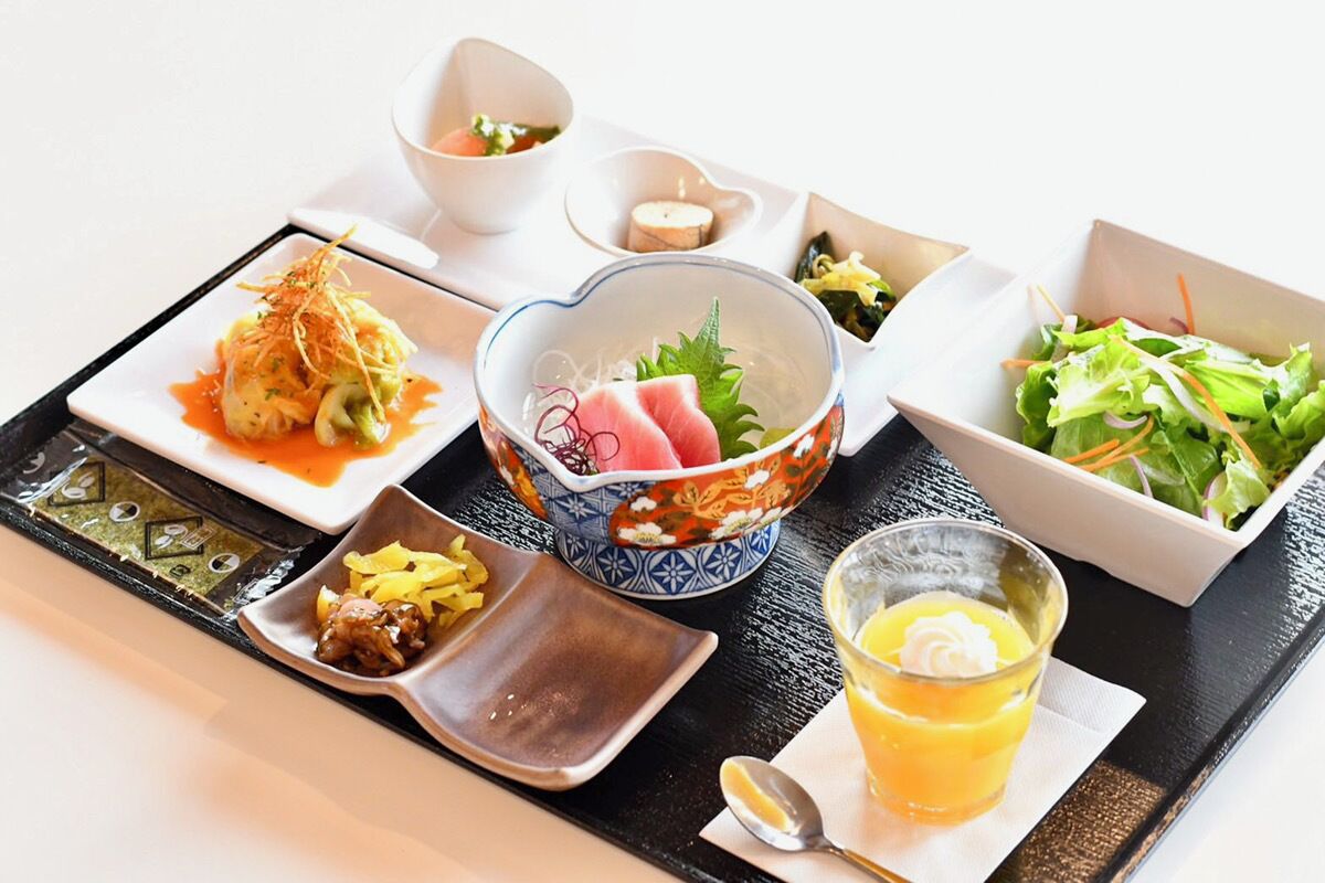 A tray with various Japanese dishes including sushi, sashimi, and a salad.