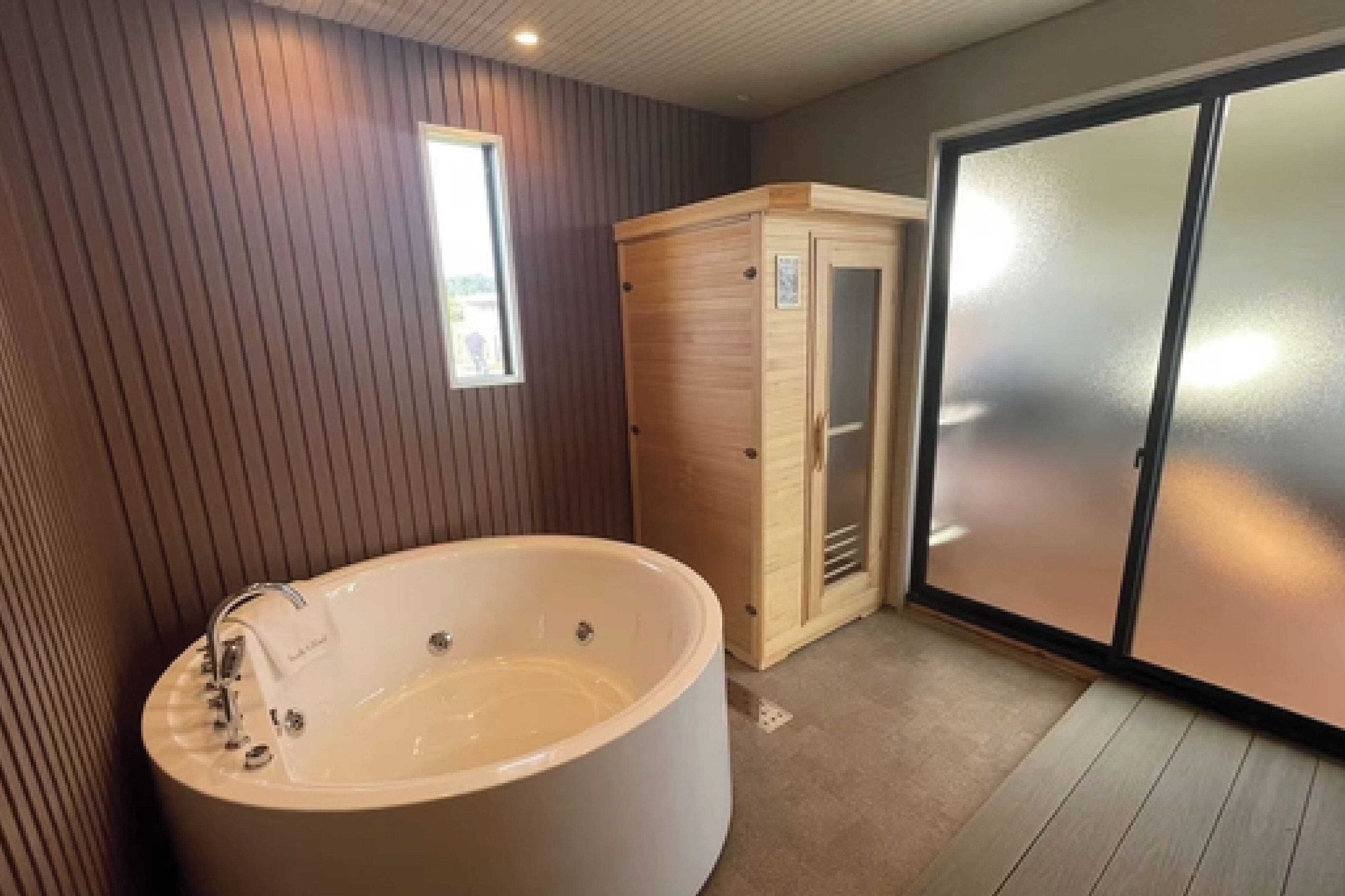 Ein modernes Badezimmer mit einer großen Badewanne, einer Sauna und einer Glastür.