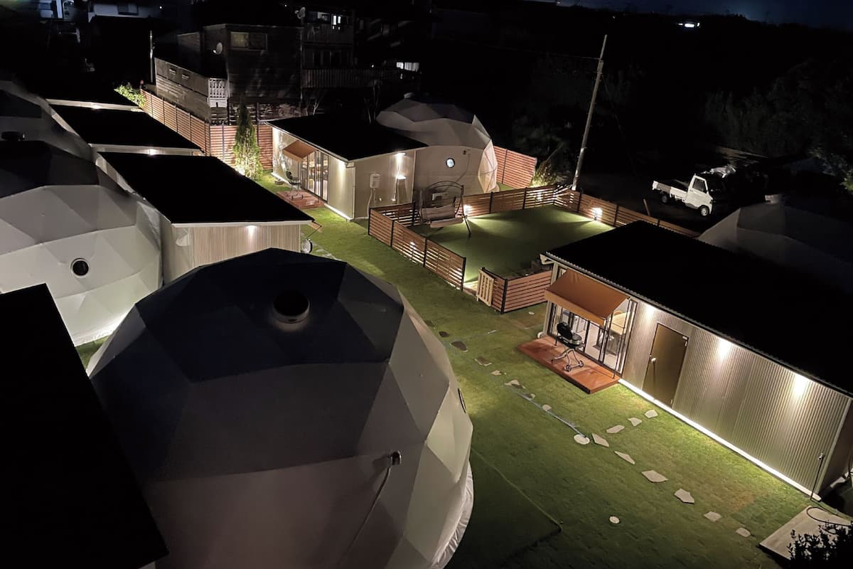 A residential area with multiple buildings, including a house with a fenced yard and a truck parked outside.
