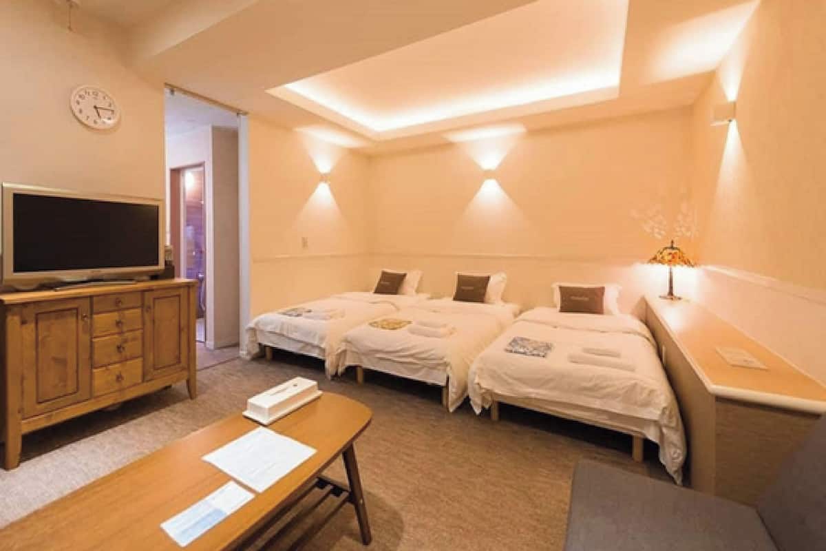 A hotel room with two beds, a TV, a desk, and a lamp.