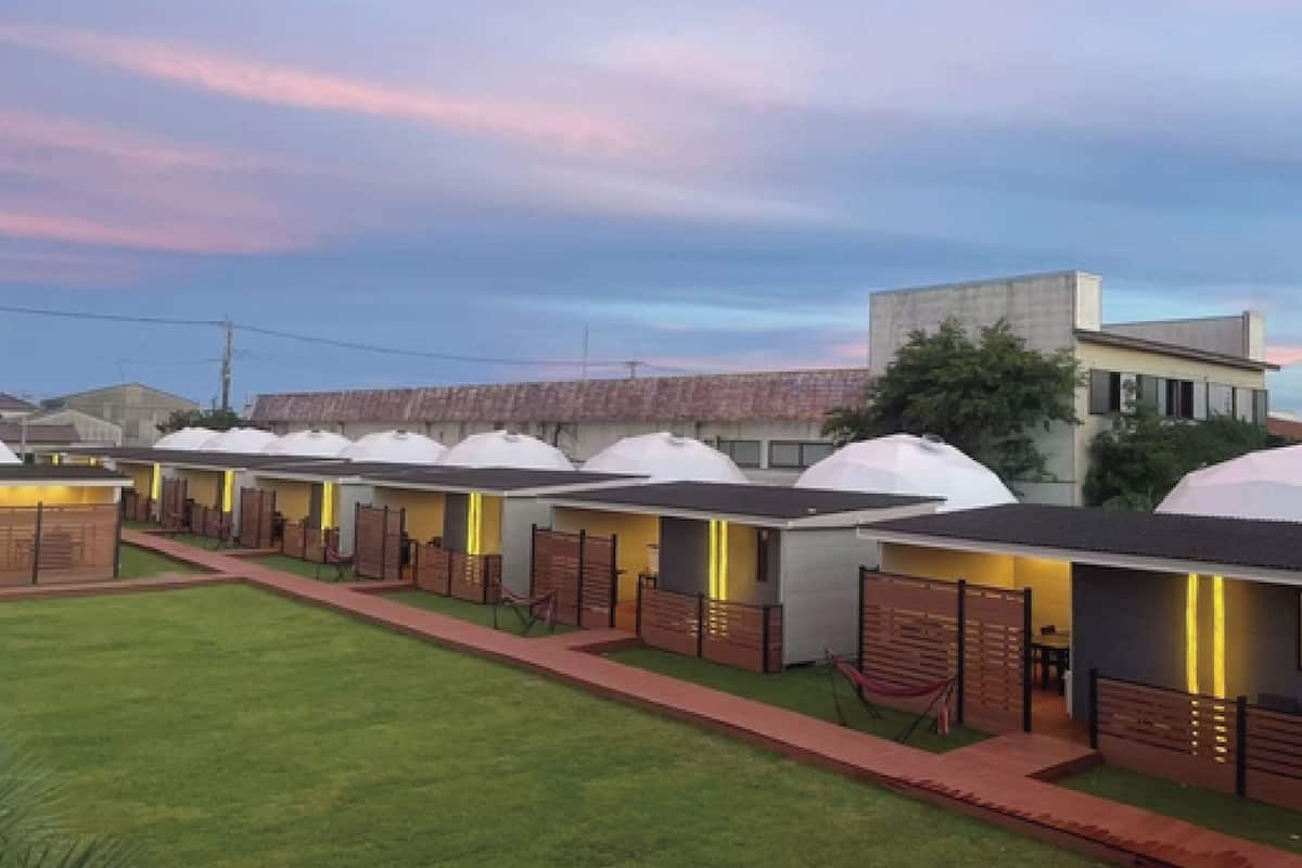 A row of modern, dome-roofed cabins with a pathway leading to a central building.